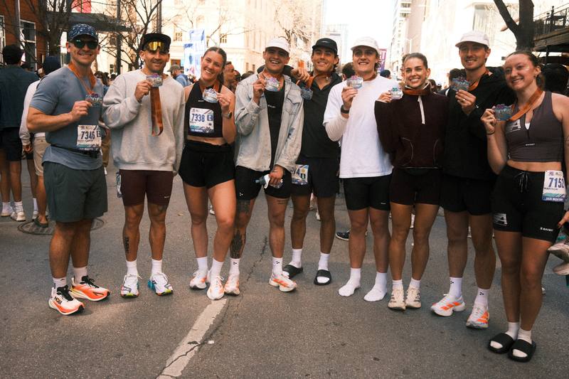 A group of Austin Marathon finishers holding up their medals in downtown Austin, Texas