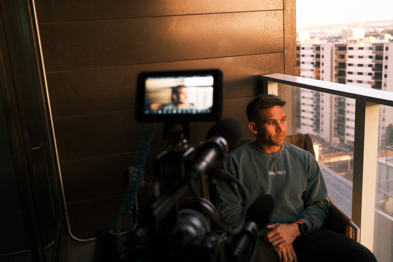 Jake Mizell's camera rig framed on the interview subject at golden hour, on a downtown Austin balcony
