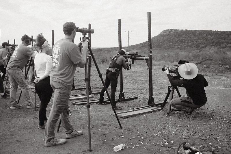 Black and white photograph of competitors and spotters working the line at a Texas shooting range