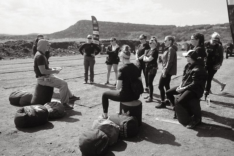 Black and white photograph of competitors and spectators gathered with range bags at a shooting match