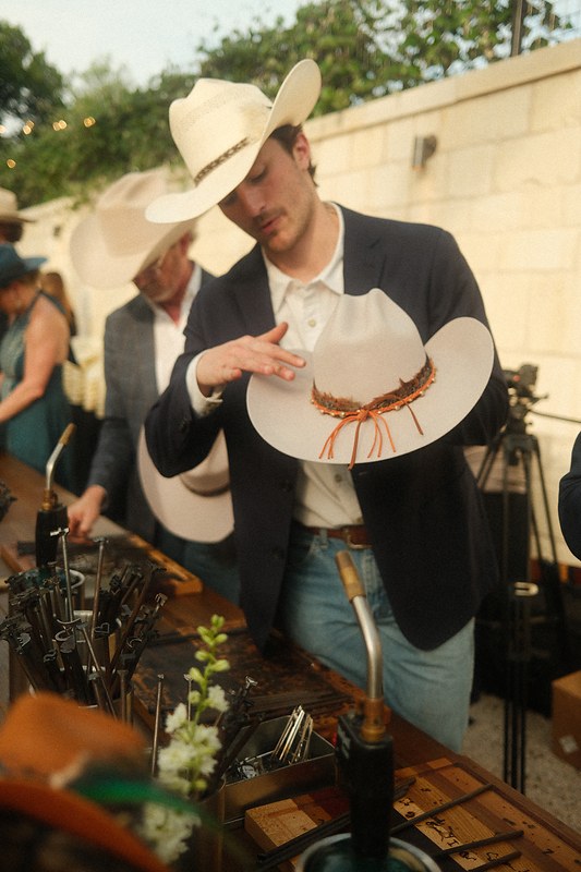 A hat maker shaping a custom western hat at a Topped Hats event, photographed by Jake Mizell